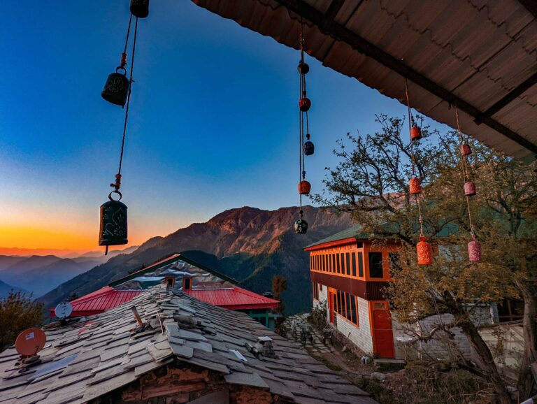 Stunning sunset over Shoja, Himachal Pradesh: Vibrant orange and pink skies casting a warm glow on the lush valleys, pine forests, and distant Himalayan peaks.