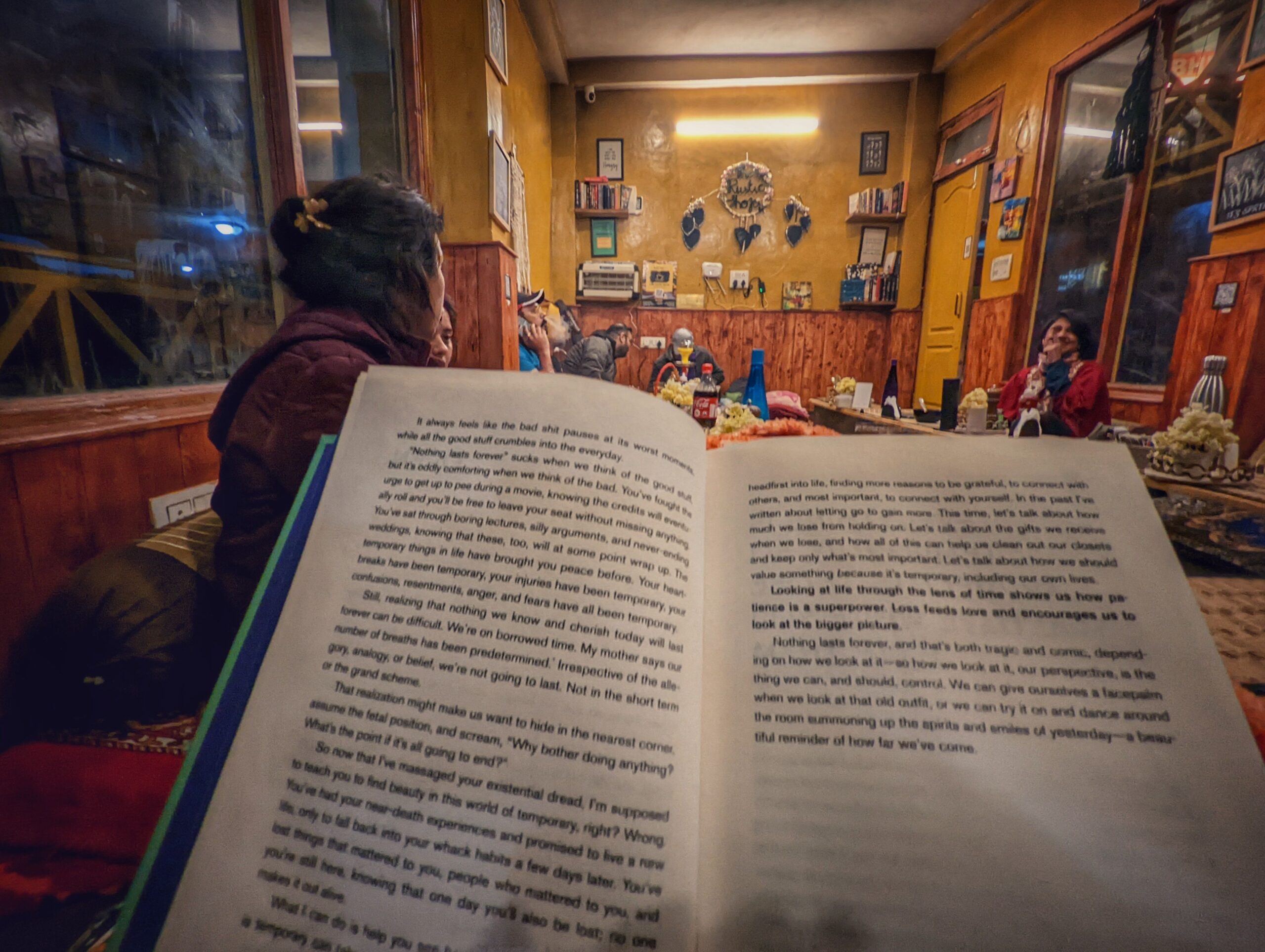 A picturesque rustic cafe in Shoja, Himachal Pradesh, surrounded by lush greenery and serene mountain views, featuring wooden architecture and cozy seating.