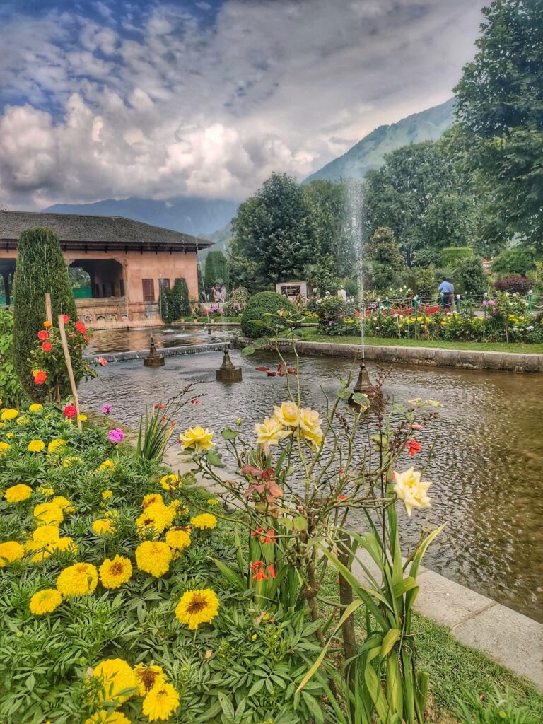 The Mughal Gardens in Srinagar, featuring beautifully landscaped terraces, colorful flowerbeds, cascading fountains, and a stunning view of the surrounding mountains.