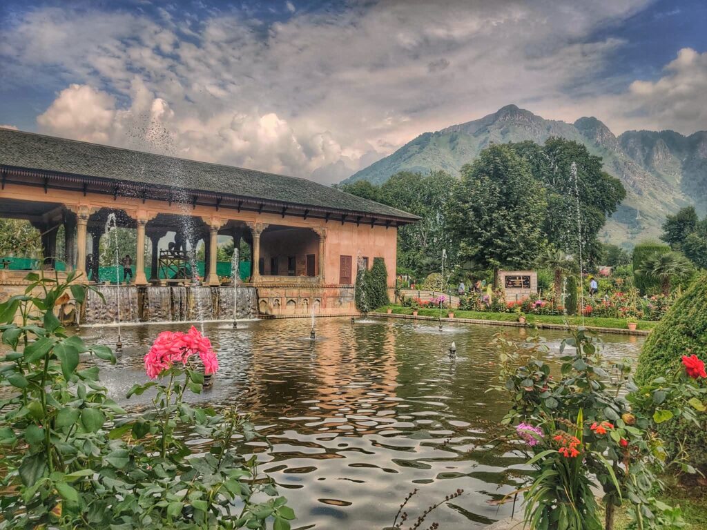 The Mughal Gardens in Srinagar, featuring beautifully landscaped terraces, colorful flowerbeds, cascading fountains, and a stunning view of the surrounding mountains.
