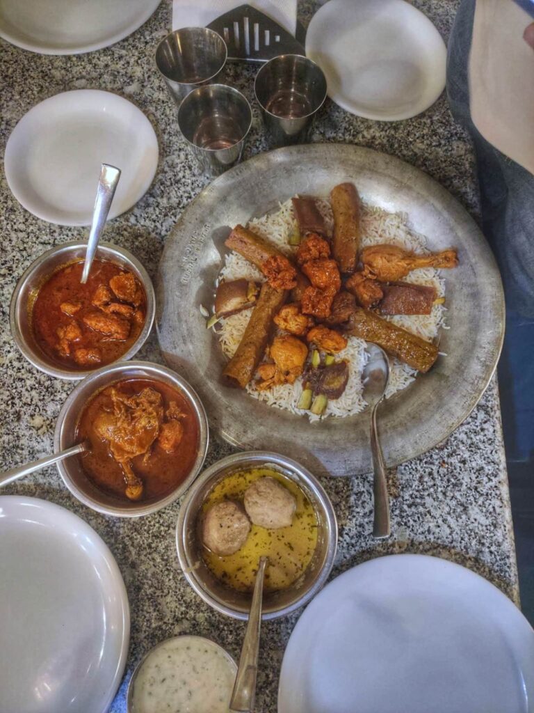 A traditional Kashmiri Wazwan feast, featuring an array of rich and flavorful dishes like Rogan Josh, Gushtaba, and Yakhni, beautifully arranged on a large platter.