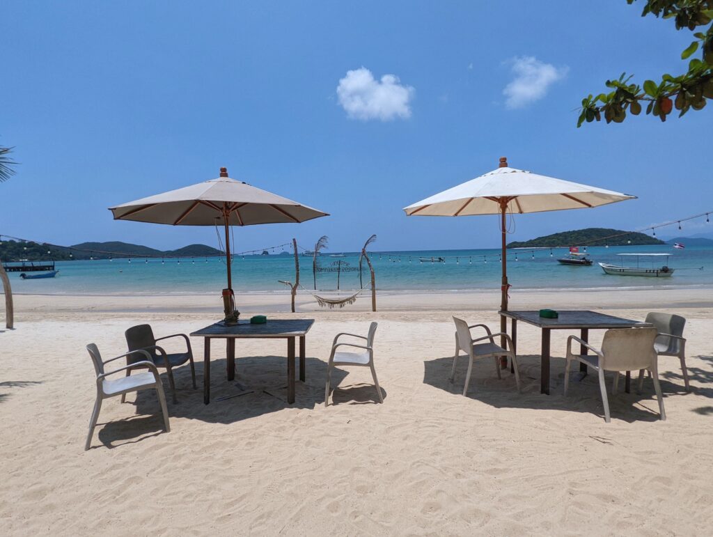 A tranquil view of Ao Soun Yai Beach on Koh Mak Island, showcasing its pristine white sand, gentle waves under a clear blue sky.