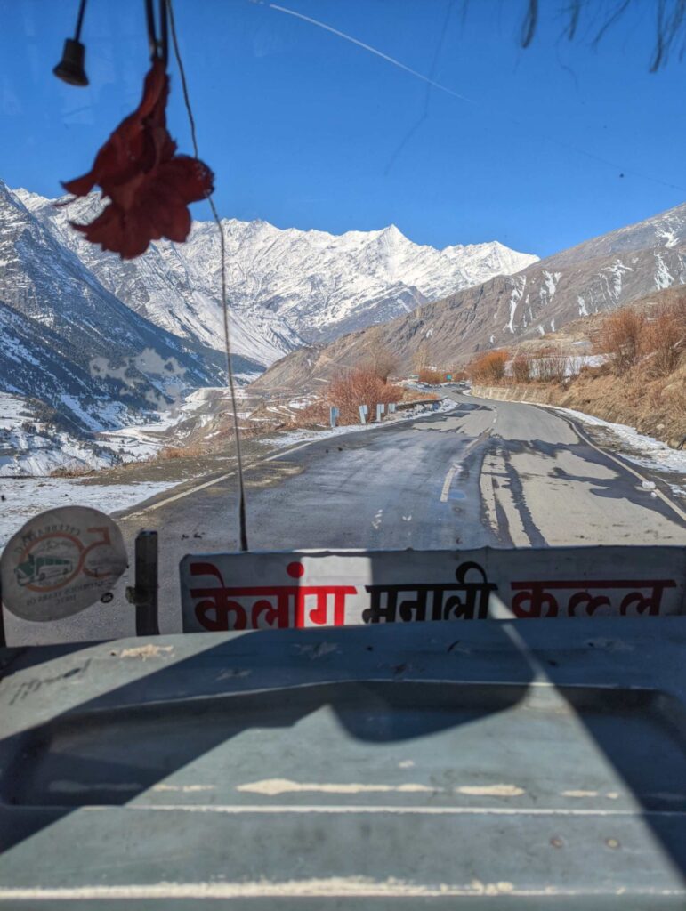 Scenic view of Lahaul Valley from the bus conductor's front seat of an HRTC bus, showcasing winding mountain roads, snow-capped peaks, and breathtaking Himalayan landscapes.
