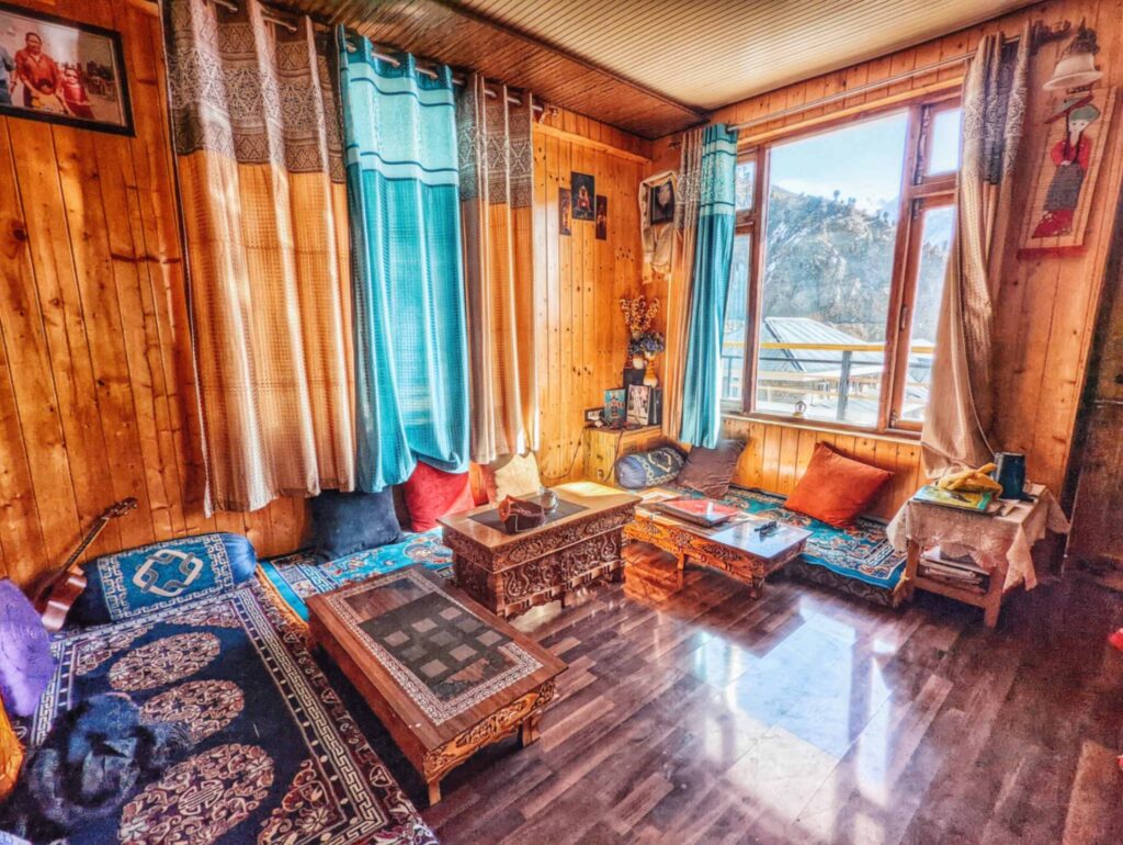 Cozy living room in Khandroling Homestay, featuring warm interiors and a stunning view of the surrounding mountains in Lahaul Valley.