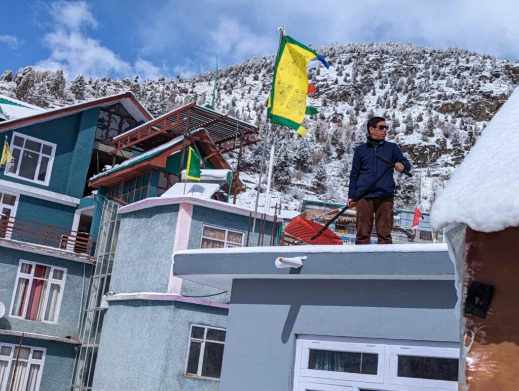 Homestay owner clearing snow from the terrace in Keylong
