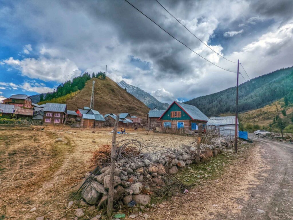 Quiet village scene in Husangam, Tulail Valley, featuring rustic wooden houses.