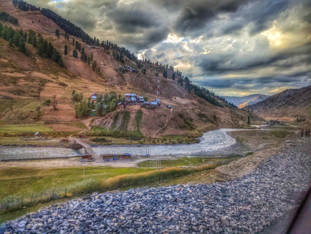 Crystal-clear blue waters of the Kishanganga River winding through rocky banks in barren mountains in of Tulail Valley