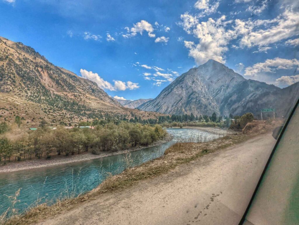 Majestic view of Habba Khatoon Peak rising sharply with its pyramid-like shape, surrounded by dense pine forests and the serene Kishanganga River flowing at its base in Gurez Valley.