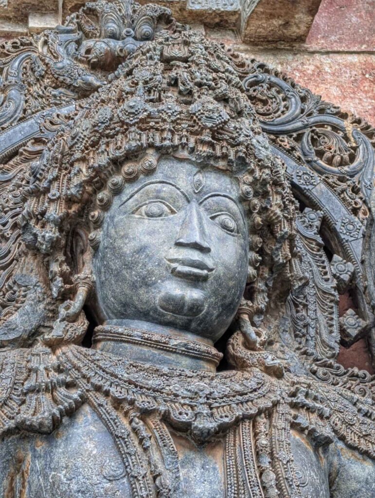 Intricately carved Hoysala temple gatekeeper statue depicting a mythological guardian figure in traditional attire, showcasing 12th-century South Indian stone sculpture craftsmanship.